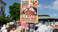 Mielenosoituskyltti ihmisten päällä sinistä taivasta vasten. Kuvassa mies syö lautaselta sydämiä virnistäen.