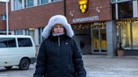Nainen seisoo Puolangan kunnanviraston edessä karvahattu päässään. 