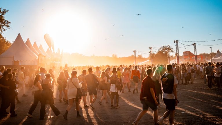 Hundratals personer går omkring på en festival. 