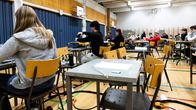 Människor sitter vid pulpeter i en gymnastiksal och skriver prov.