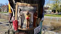 En stickad garninstallation på ett träd vid en å med virkade figurer av humorgruppen KAJ.