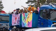 Abit heittävät karkkia korkealle ilmaan sinisestä kuorma-autosta, joka ajaa letkassa muiden samanlaisten kanssa.