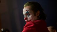 Närbild på Joker (Joaquin Phoenix) iklädd clownmask och röd kostym.