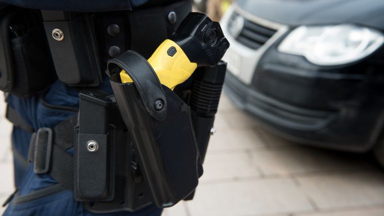 Gult elchockvapen som sitter fast i polisens bälte. 