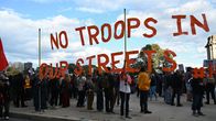 Verkkoaita johon kirjoitettu No troops in our streets. Mielenosoittajia. 