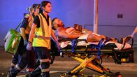 Ambulanssihenkilökunta kantaa loukkaantunutta miestä paareilla pois.