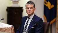 Hegseth istuu vakavana sinisessä puvussa ja valkoraitaisessa sinisessä kravatissa pöydän ääressä. Hänen taskuliinansa on Yhdysvaltain lipun väreissä.
