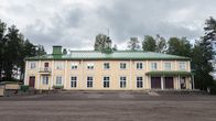 Orimattilan Jymylinna, eli vaalea matala puinen rakennus, jossa on vihreä katto, paljon ikkunoita kahdessa tasossa ja katettu pääsisäänkäynti.