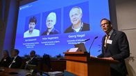 En man står vid en talarstol framför en projekterad bild med namnen Karl Deisseroth, Peter Hegemann och Georg Nagel.