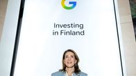 En kvinna står framför en skylt med Googles logotyp och texten "Investing in Finland".