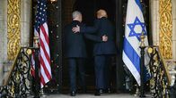 Netanjahu ja Trump pitelevät toisiaan selästä ja kävelevät rakennukseen sisään. Oven reunoilla Yhdysvaltain sekä Israelin liput.