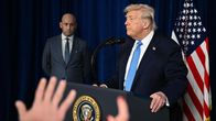 Stephen Miller taustalla, Donald Trump edessä puhumassa mikrofoniin.