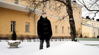 Henkilö seisoo rakennuksen edustalla talvisessa maisemassa.
