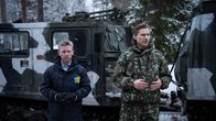 Ruotsin ja Suomen puolustusministerit seisovat maastossa takanaan armeijan ajoneuvo.