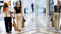 Two young women walk through a shopping centre carrying shopping bags.