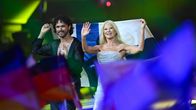 Pete Parkkonen och Linda Lampenius håller upp Finlands flagga när de går på scen.