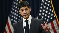 Kevin Warsh står och talar framför amerikanska flaggor.
