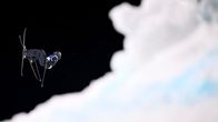 Freeski-laskija hyppää ilmaan, edustalla lumikasa.