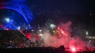 Eiffel-tornin juurella juhlitaan ilotulituksin ja soihtujen valossa Pariisin yössä.