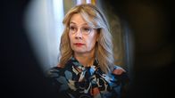 Silmälasipäinen nainen lehdistötilaisuudessa.