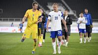 Finska fotbollsspelare i gula och vita matchställ går tillsammans på en fotbollsplan efter en match.