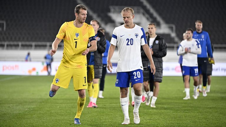 Finska fotbollsspelare i gula och vita matchställ går tillsammans på en fotbollsplan efter en match.
