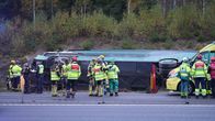 Räddningspersonal står vid en buss som ligger på sidan i diket.