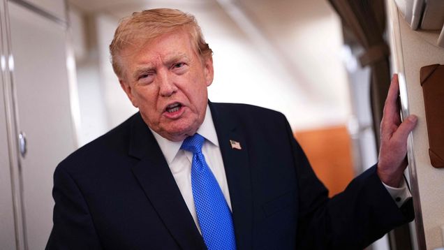 Yhdysvaltain presidentti Donald Trump nojaa seinään ja puhuu toimittajille lentokoneessa.