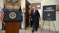 Donald Trump tågar in i ett finrum med talarstol.