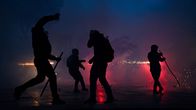 Fyra personer med masker och stavar står i rök, en person kastar ett föremål.