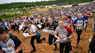 Suuri joukko suunnistajia lähtee liikkeelle kilpailun lähtöalueelta metsän reunalla: