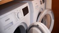 Front-loading white washing machine and dryer, both with doors slightly open.