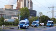 Voimalaitos, jonka edessä kolme poliisiautoa.