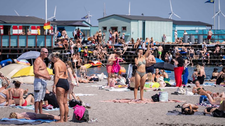 En badstrand i gassande sol som är full av människor.