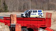 Ihmisiä poliisiauton luona hiekkatiellä pellon vieressä.