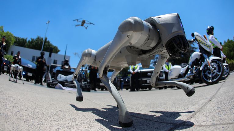 En robothund syns i förgrunden. I bakgrunden syns ytterligare högteknologisk policiär utrustning.