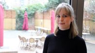 Helena Quis framför en fönstervägg mot en bakgård.