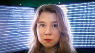 Emilia Laurila katsoo kameraan ja taustalla sinisiä valoja