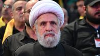 Naim Qassam istuu mustassa vaattessa vaalea turbaani päässä yleisössä.