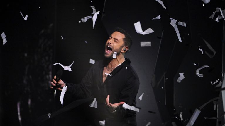 Måns Zelmerlöw laulaa lavalla paperi silpun lentäessä ilmassa.
