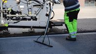 Työntekijä suoristaa vastapestyä asfalttia kadun päällystötyömaalla.