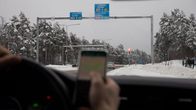 Mies räplää matkapuhelinta ajaessa autoa.