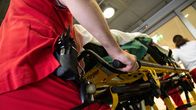 Ensihoitaja kuljettaa potilasta ambulanssista hoitoon.
