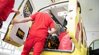 A paramedic moves a patient out of an ambulance.