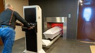 Krematorion polttouunin luukku on auki ja arkkua työnnetään sisään.