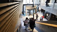 Aurumin aula ja pääsisäänkäynti. Opiskelijoita kävelemässä alas portaita ja aulassa.