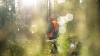 Metsästäjä aseen kanssa metsässä.