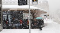 Rikligt snöfall på salutorget i Åbo. På bilden en person med paraply. I bakgrunden står ett gäng personer under skydd.
