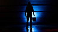 Photo shows a person standing with a bucket in their hand.