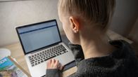 Ung person skriver studerar vid bärbar dator. 